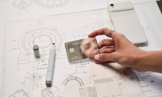An American Express Business Platinum card against a backdrop of architectural drawings.