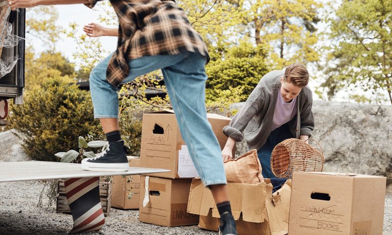 Couple helping each other while arranging cardboard boxes outside van