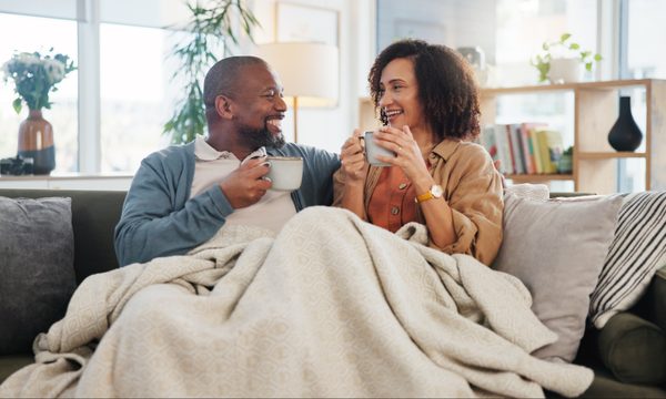 older adult couple sharing coffee on sofa