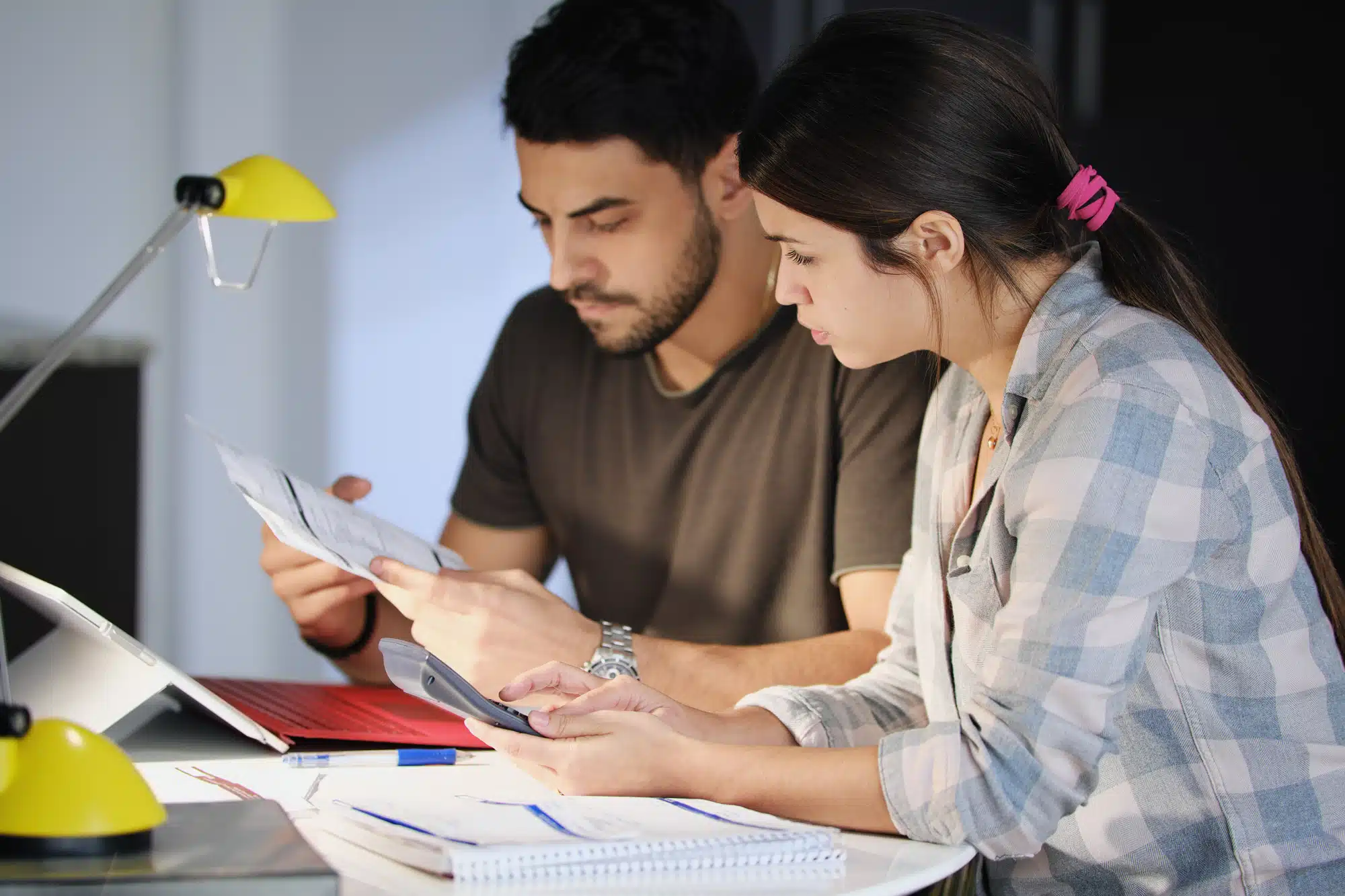 A couple reviewing a budget worksheet at their kitchen table