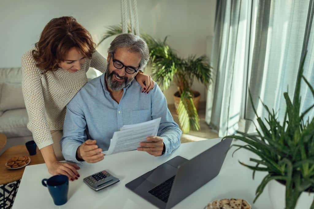 A couple reviews financial paperwork together while planning savings goals.
