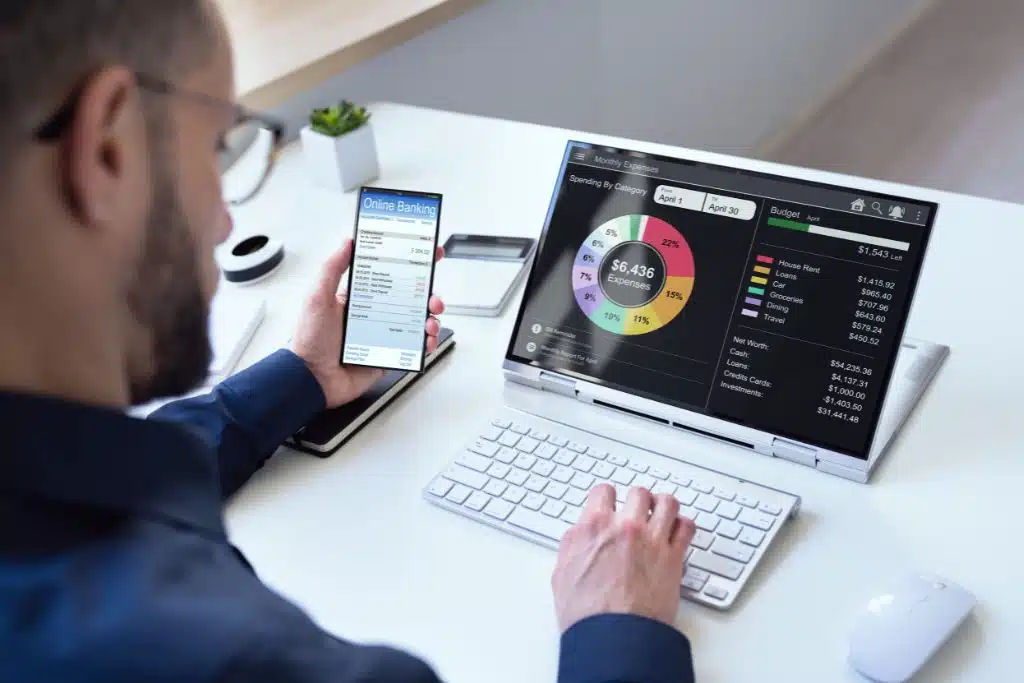 Man reviewing his budget with a tablet, cell phone, at his desk