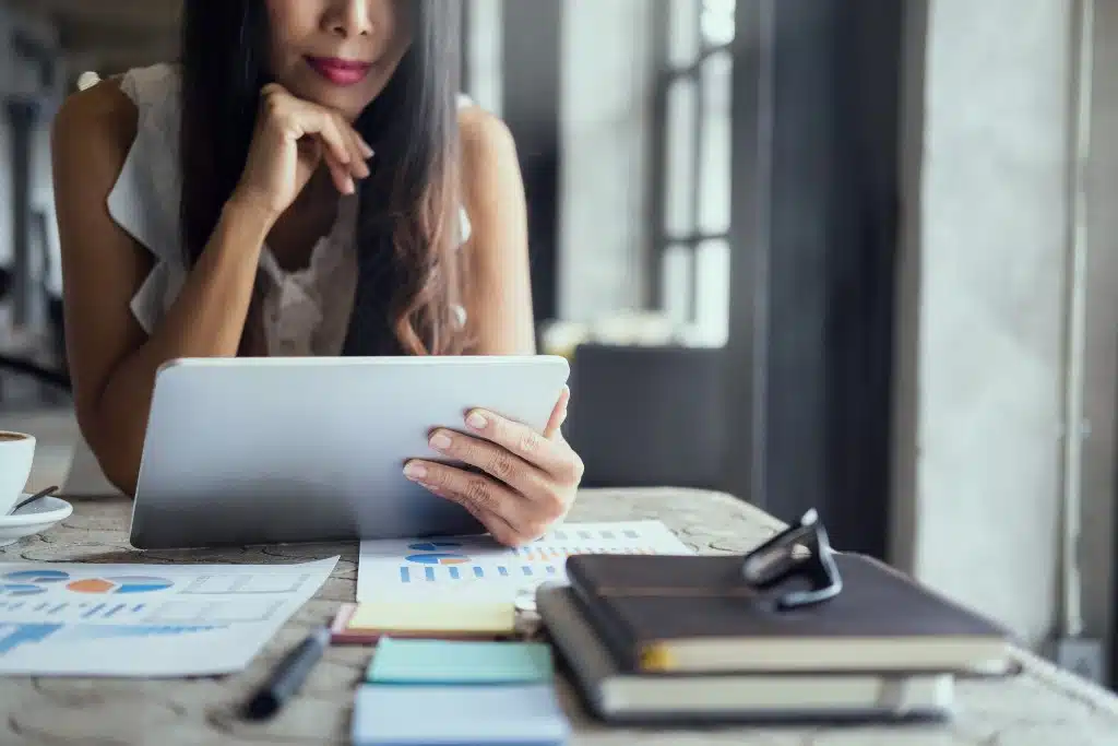 Young adult researching investments with coins and piggy bank on desk