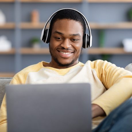 A man watching a video on personal finance on his laptop with a smile, indicating engagement